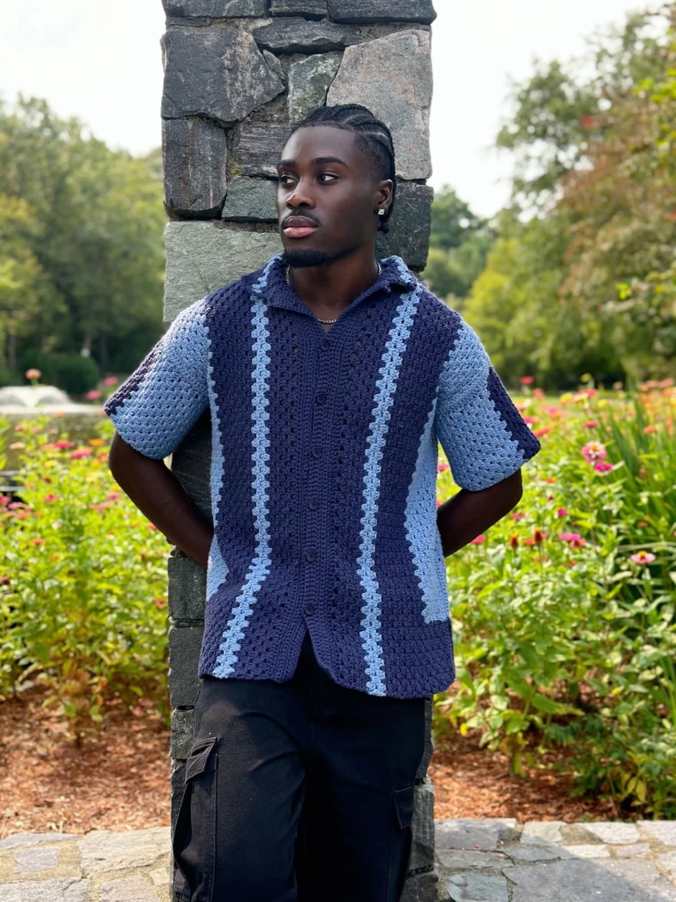 A man wearing a crocheted short-sleeve button-up in navy and light blue stripes