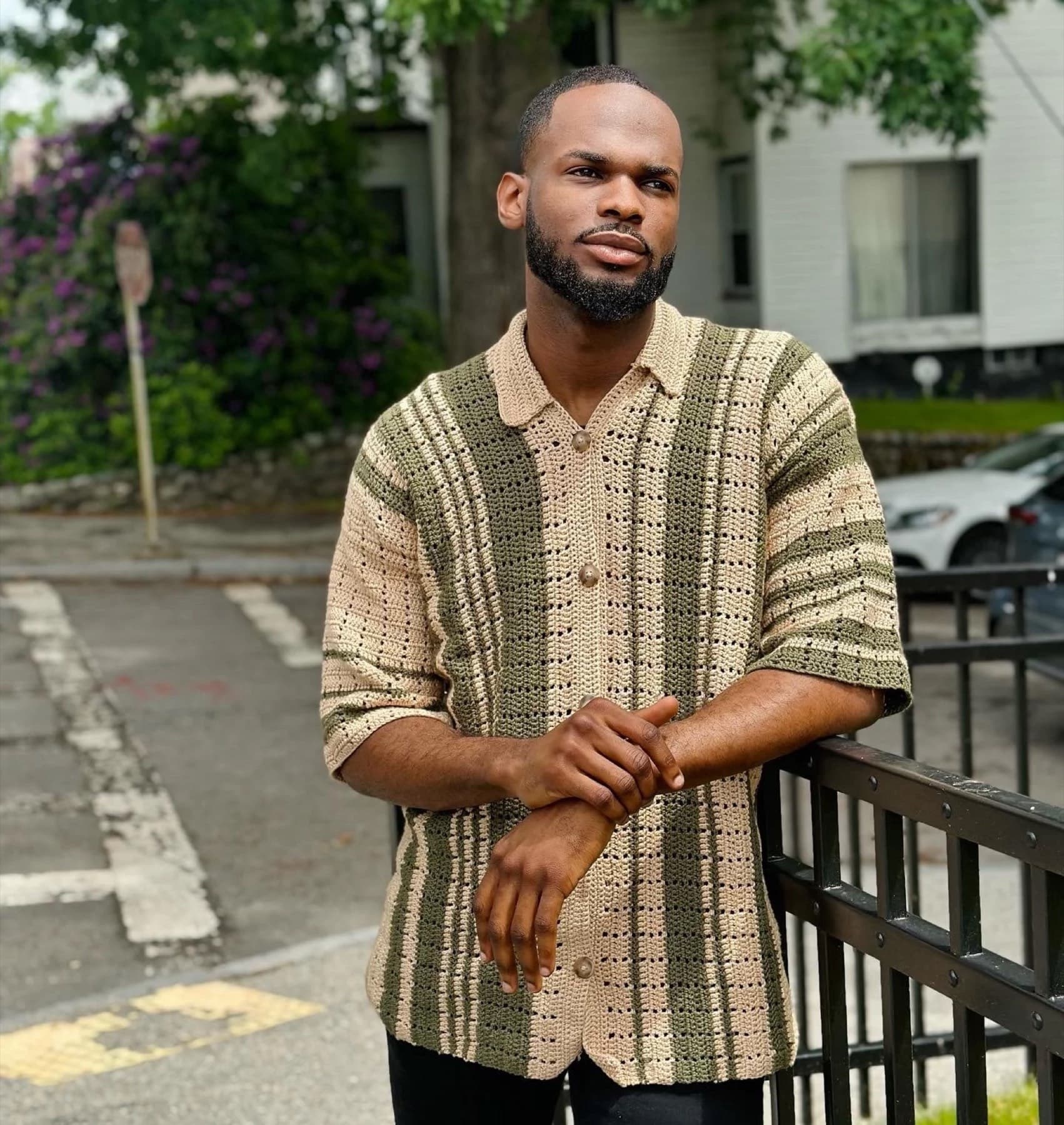 A man wearing a crocheted short-sleeve button-up in cream with olive stripes