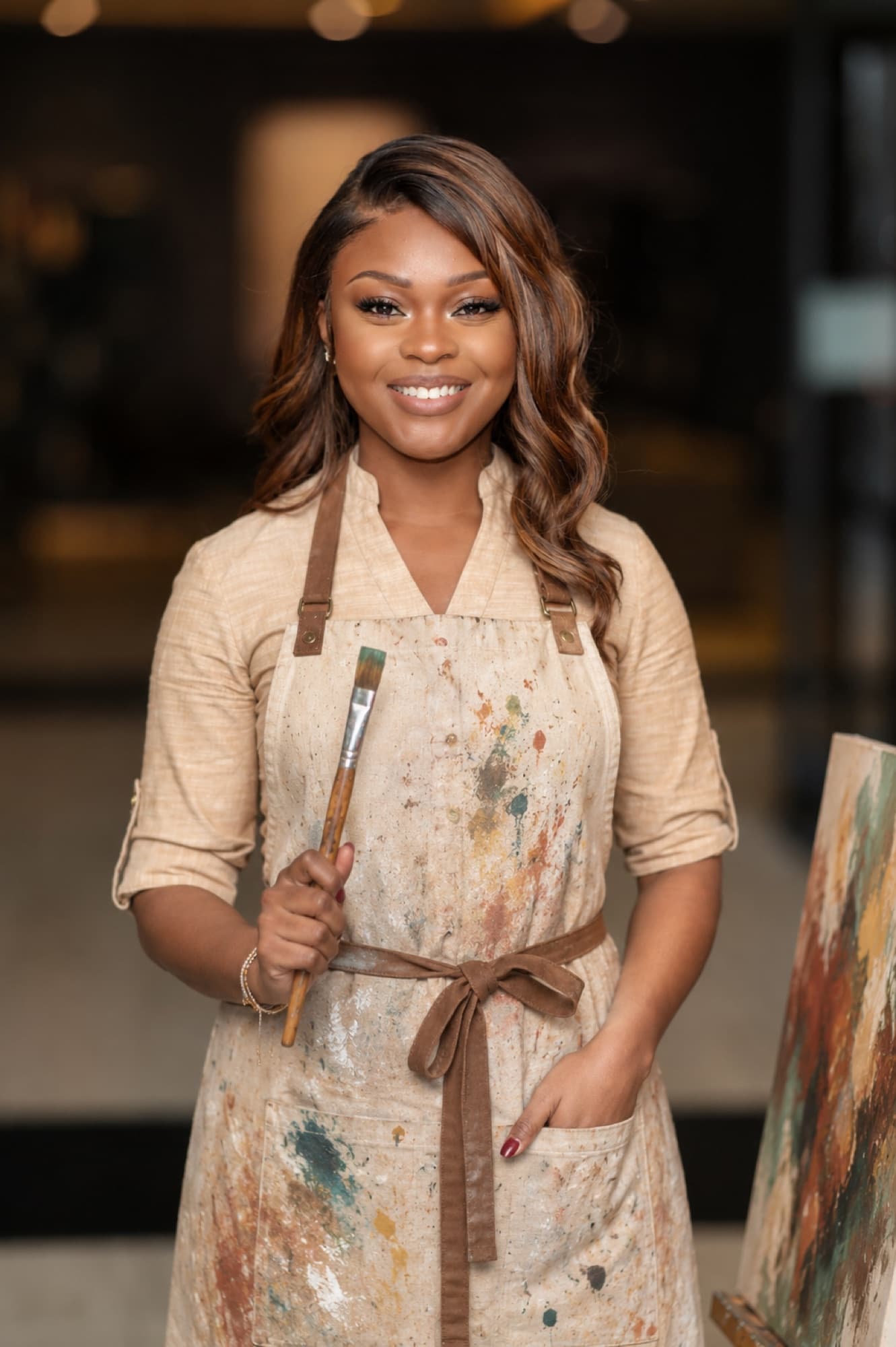 Ivey in a paint-stained apron, holding brushes in her studio